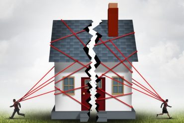 Broken family after a bitter divorce settlement and separation with a couple in a bad relationship breaking a house apart showing the concept of a marriage dispute and dividing assets