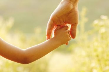 parent holds the hand of a small child